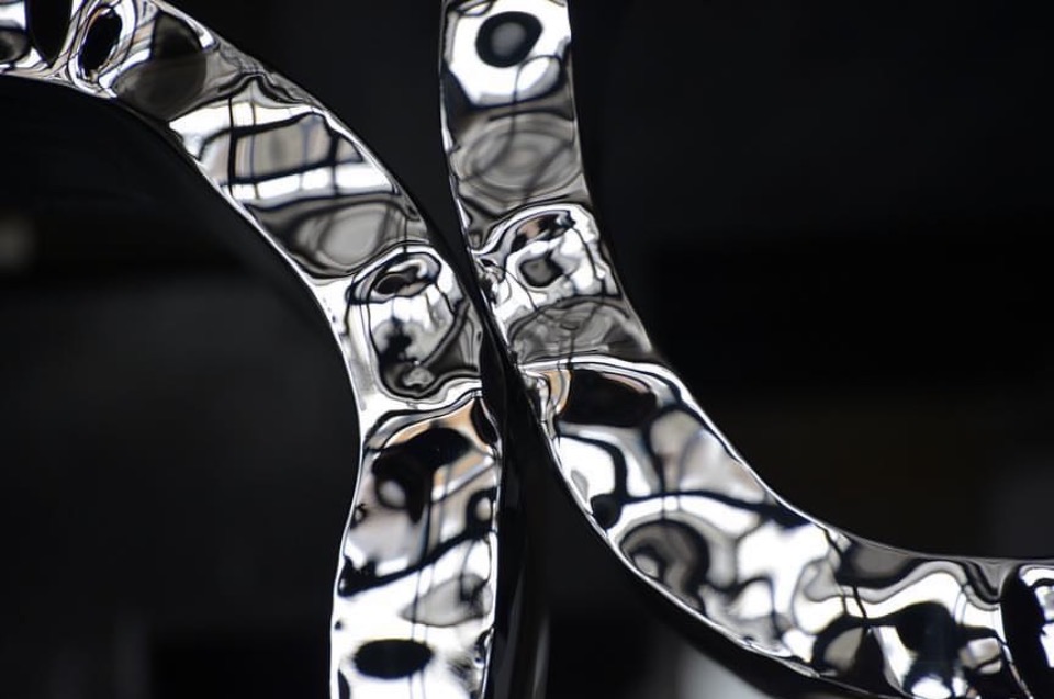 Mirror-polished stainless steel sculptural rings with rippled reflective surface