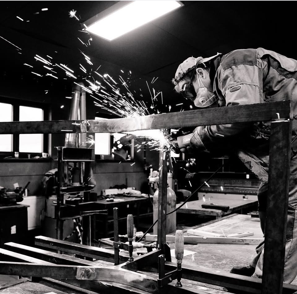 Metalworker grinding a steel frame with sparks flying, black and white